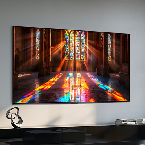 Wall-mounted Samsung OLED 4K TV showing stained glass cathedral scene with deep blacks and bright highlights